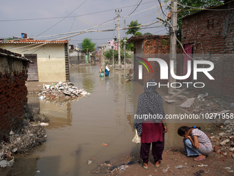 Residents wade through a waterlogged street to reach their homes in a low-lying area, after a rise in the waters of river Yamuna due to heav...