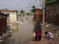 Residents wade through a waterlogged street to reach their homes in a low-lying area, after a rise in the waters of river Yamuna due to heav...