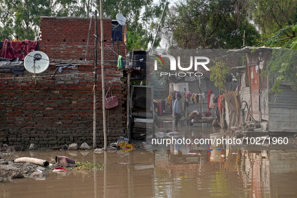 A man dries clothes in a waterlogged street outside his home in a low-lying area, after a rise in the waters of river Yamuna due to heavy mo...