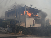 Flames engulf a house  as a wildfire rages in Saronida near Athens, Greece on July 17, 2023. (