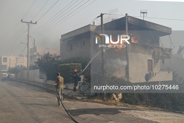 A firefighter operates  as flames engulf a house in Saronida near Athens, Greece on July 17, 2023. 