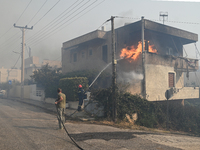 A firefighter operates  as flames engulf a house in Saronida near Athens, Greece on July 17, 2023. (