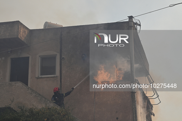 A firefighter operates  as flames engulf a house in Saronida near Athens, Greece on July 17, 2023. 