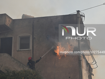 A firefighter operates  as flames engulf a house in Saronida near Athens, Greece on July 17, 2023. (