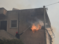 A firefighter operates  as flames engulf a house in Saronida near Athens, Greece on July 17, 2023. (