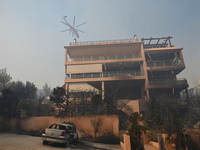 A firefighting helicopter flies over a house damaged by a raging wildfire in Saronida near Athens, Greece on July 17, 2023. (