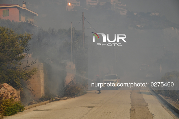 A firefighter operates  as a wildfire rages inside the residential area of Saronida near Athens, Greece on July 17, 2023. 