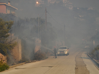 A firefighter operates  as a wildfire rages inside the residential area of Saronida near Athens, Greece on July 17, 2023. (