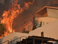 Flames engulf a house  as a wildfire rages in Saronida near Athens, Greece on July 17, 2023. (