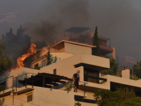 Flames engulf a house  as a wildfire rages in Saronida near Athens, Greece on July 17, 2023. (