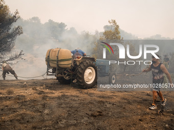 

Locals are helping firefighters to extinguish the fire in Nea Zoi in Nea Peramos, a place near Megara, Greece on July 19, 2023. After thre...