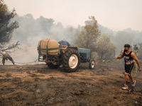 

Locals are helping firefighters to extinguish the fire in Nea Zoi in Nea Peramos, a place near Megara, Greece on July 19, 2023. After thre...