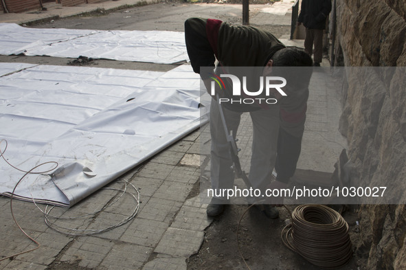 A man prepares a rope to raise the curtains  on Bustan Alqasr district in Aleppo city on 1st February 2016.
