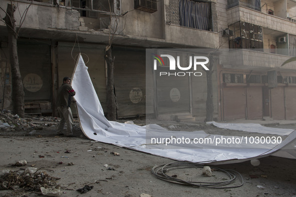 a man pulling the curtains  on Bustan Alqasr district in Aleppo city on 1st February 2016.
