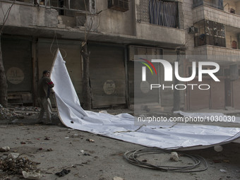 a man pulling the curtains  on Bustan Alqasr district in Aleppo city on 1st February 2016.
(