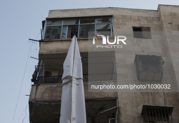 A man raise curtains to the top of the building  on Bustan Alqasr district in Aleppo city on 1st February 2016.
