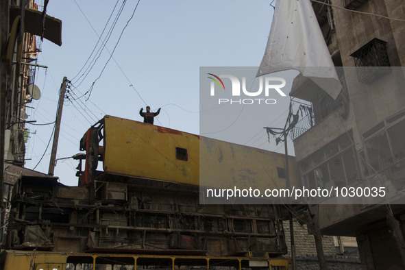 A man stands above wrack buses were in place to protect civilians from sniper regime forces  on Bustan Alqasr district in Aleppo city on 1st...