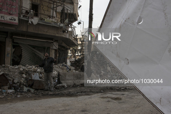 A man pulling the curtains  on Bustan Alqasr district in Aleppo city on 1st February 2016.
