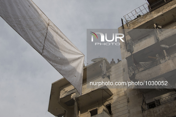 two men are tieding ropes curtains on top of the building  on Bustan Alqasr district in Aleppo city on 1st February 2016.
