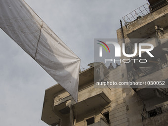 two men are tieding ropes curtains on top of the building  on Bustan Alqasr district in Aleppo city on 1st February 2016.
(