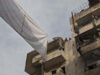two men are tieding ropes curtains on top of the building  on Bustan Alqasr district in Aleppo city on 1st February 2016.
(