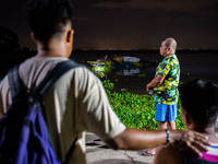 People look at the capsized boat in Laguna Lake that killed more than 20 people, in Binangonan, Rizal Province, Philippines, on July 27, 202...