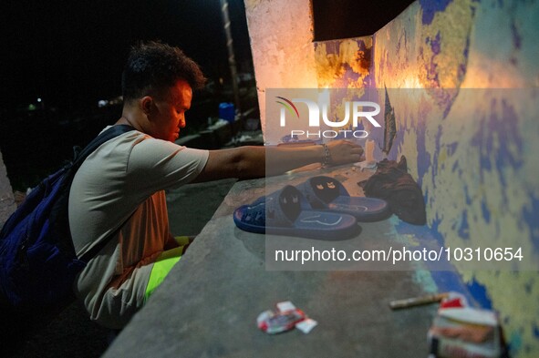 A man lights a candle at the port where a boat capsized, killing more than 20 people, in Laguna Lake, Binangonan, Rizal Province, Philippine...