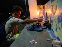 A man lights a candle at the port where a boat capsized, killing more than 20 people, in Laguna Lake, Binangonan, Rizal Province, Philippine...