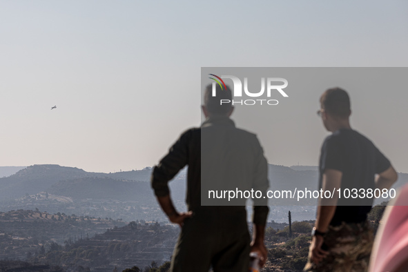 Two men of the Fire Department watch a plane patrolling the area, Alassa, Cyprus, on Aug. 5, 2023. Fire Department and Forest Department uni...