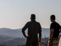 Two men of the Fire Department watch a plane patrolling the area, Alassa, Cyprus, on Aug. 5, 2023. Fire Department and Forest Department uni...