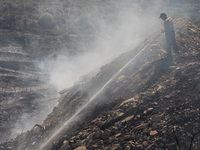 A Limassol Municipality worker throws water over a smoking area, Alassa, Cyprus, on Aug. 5, 2023. Fire Department and Forest Department unit...