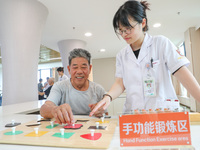  An elderly man is escorted by medical staff during rehabilitation training at the ''Rehabilitation Home'', a community health service cente...