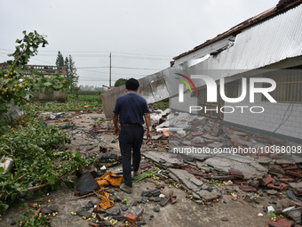 A citizen passes a damaged house after a tornado in Dafeng district, Yancheng city, Jiangsu province, China, August 14, 2023. It is understo...