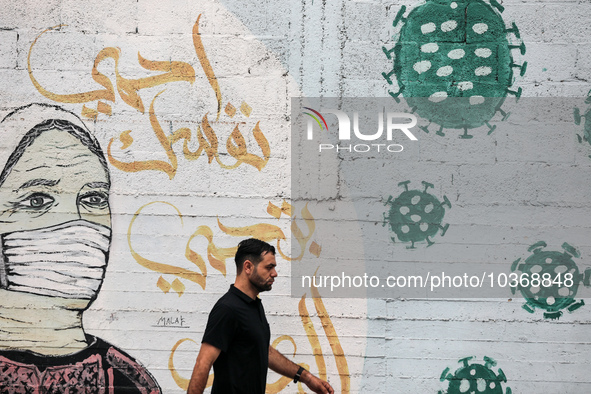 A Palestinian man walks past street art showing a Covid-19 coronavirus in Gaza City, on August 14, 2023. The number of new Covid-19 cases re...