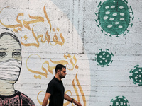 A Palestinian man walks past street art showing a Covid-19 coronavirus in Gaza City, on August 14, 2023. The number of new Covid-19 cases re...