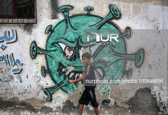 A Palestinian boy walks past street art showing a Covid-19 coronavirus in Gaza City, on August 14, 2023. The number of new Covid-19 cases re...