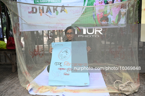 Activist of a social organization hold a placard while sitting inside a mosquito net during an awareness campaign against mosquito-borne dis...