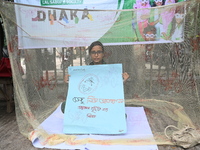 Activist of a social organization hold a placard while sitting inside a mosquito net during an awareness campaign against mosquito-borne dis...