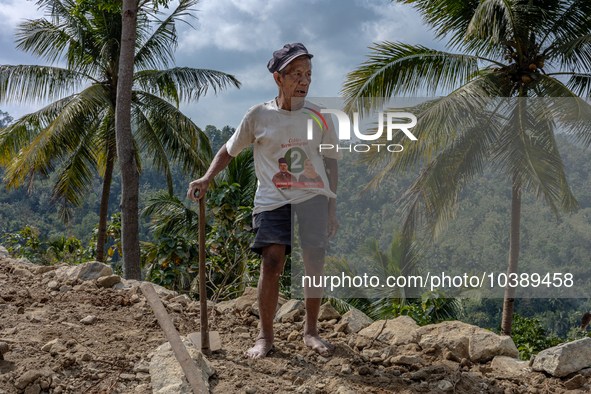 A man holds a hoe, as he helps villagers to renovate a broken village road at Kebumen, Central Java, Indonesia on August 20, 2023.  