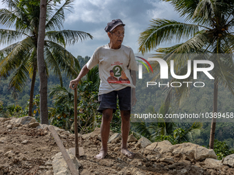 A man holds a hoe, as he helps villagers to renovate a broken village road at Kebumen, Central Java, Indonesia on August 20, 2023.  (