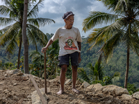 A man holds a hoe, as he helps villagers to renovate a broken village road at Kebumen, Central Java, Indonesia on August 20, 2023.  (