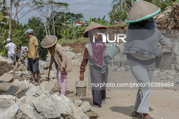 Women carries a bucket of sand and stone as they help villagers to renovate a broken village road at Kebumen, Central Java, Indonesia on Aug...