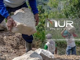 A man carries a big stone as he helps villagers to renovate a broken village road at Kebumen, Central Java, Indonesia on August 20, 2023.  (