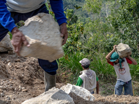 A man carries a big stone as he helps villagers to renovate a broken village road at Kebumen, Central Java, Indonesia on August 20, 2023.  (