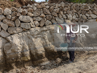 A woman stands in a broken road during the road renovation at Kebumen, Central Java, Indonesia on August 20, 2023.  (