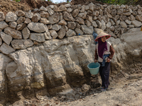 A woman stands in a broken road during the road renovation at Kebumen, Central Java, Indonesia on August 20, 2023.  (