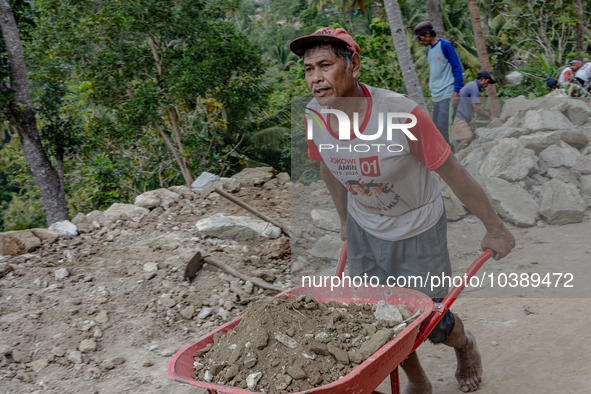 A man pulls a crate full of big stone as he helps villagers to renovate a broken village road at Kebumen, Central Java, Indonesia on August...