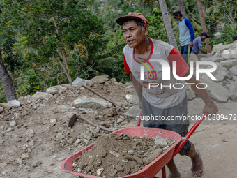 A man pulls a crate full of big stone as he helps villagers to renovate a broken village road at Kebumen, Central Java, Indonesia on August...