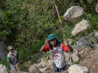 A man throws a big stone as he helps villagers to renovate a broken village road at Kebumen, Central Java, Indonesia on August 20, 2023.  (