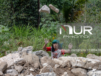 A man throws a big stone as he helps villagers to renovate a broken village road at Kebumen, Central Java, Indonesia on August 20, 2023.  (